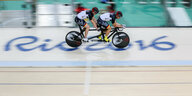 Ein Radsportler-Duo sprintet auf dem Tandem in einer Arena über den Bodenschriftzug Rio 2016