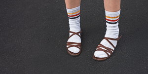 Eine Person trägt weiße Socken mit Ringeln in den Deutschlandfarben in Sandalen