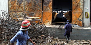 Männer in Schutzkleidung vor einem teilzerstörten Gebäude