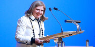 Sibylle Lewitscharoff steht lachend an einem Podium mit Mikrofonen