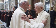 Der neue und der alte Papst umarmen sich.