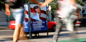 Menschen laufen vor einem Wahlplakat Norbert Hofers vorbei