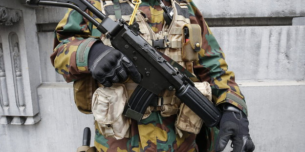 Ein Mensch in Uniform hält sein Gewehr vor der Brust