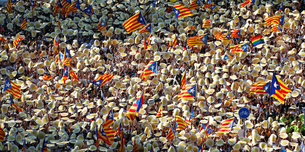 Eine Menschenmenge, man sieht nur beigefarbene Hüte und katalanische Fahnen