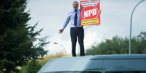 Udo Pastörs steht auf einem weißen Lieferwagen und hält ein NPD-Plakat in der Hand