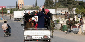 Frauen in einem Hilfskonvoi in Syrien bei Damaskus lachen und winken