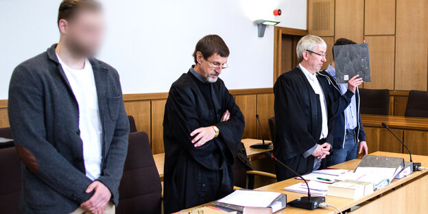 vier Männer in einem Gerichtssaal, zwei Gesichter sind verpixelt