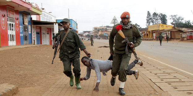 Kongolesische Soldaten schleifen einen Demonstranten über eine Straße