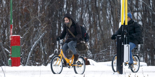 Zwei Migranten fahren mit Fahrrädern durch den Schnee über die Grenze in Storskog