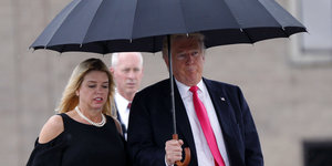 Trump und Pam Bondi laufen unter einem Regenschirm