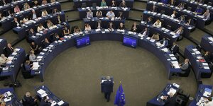 Jean-Claude Juncker steht unten im Auditorium den EU-Abgeordneten gegenüber