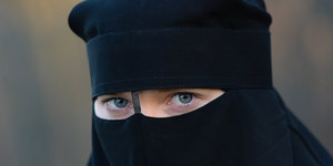 Nur die blauen Augen der Frau gucken durch den Niqab hindurch