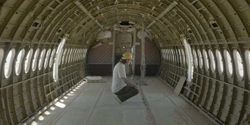 Ein Mann kniet in einem Flugzeugskelett