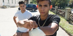 Ein junger Mann zeigt eine Mullbinde an seinem Arm