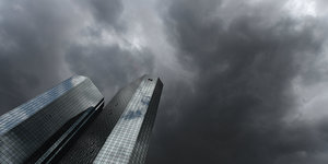 Das Hochhaus der Deutschen Bank in Frankfurt am Main vor dunklen Wolken