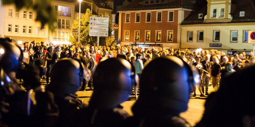 Neonazis stehen hinter einer Polizeikette auf dem Kornmarkt in Bautzen