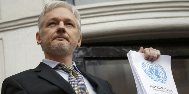 Julian Assange hält den UN-Bericht in der Hand