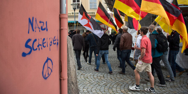 Männer mit deutschen Nationalflaggen laufen durch die Innenstadt von Bautzen, auf einer Hauswand steht „Nazi Scheiße!“