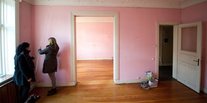zwei Frauen in einer leeren Wohnung mit rosafarbenen Wänden