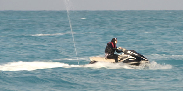 Eine Burkini-Trägerin steuert einen Jetski auf dem Wasser