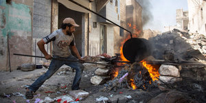 Ein Mann macht auf offener Straße in Aleppo ein Feuer
