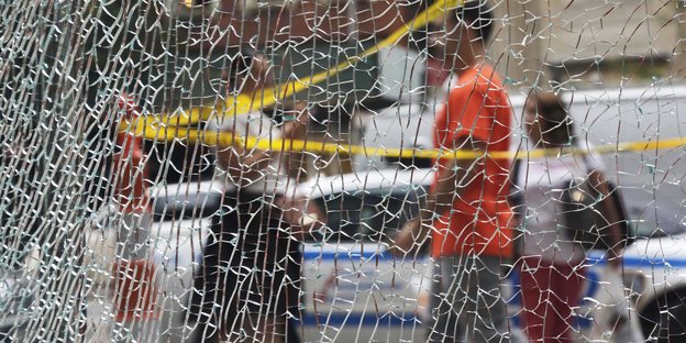 Eine durch die Explosion stark beschädigte Fensterscheibe in Manhattan, im Hintergrund Fußgänger