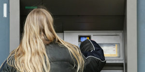 Eine Frau steht an einem Bankautomaten