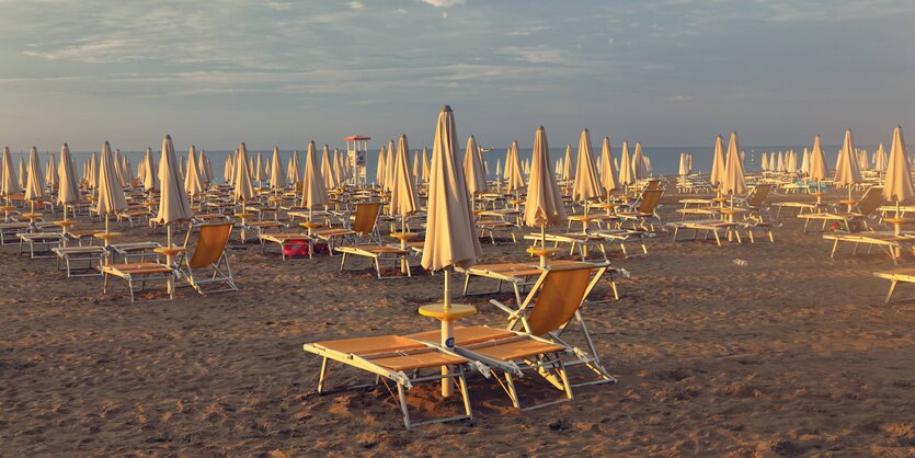 Sonnenschirme und Liegen stehen auf Sand