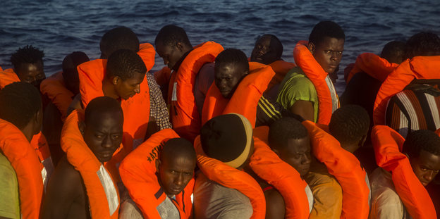 Viele Flüchtlinge stehen - alle eingezwängt in orange Schwimmwesten, an Bord eines Schiffes