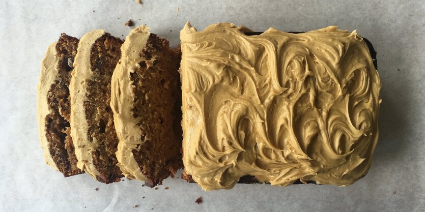 Ein brauner Kuchen mit beigefarbenem Topping liegt angeschnitten da