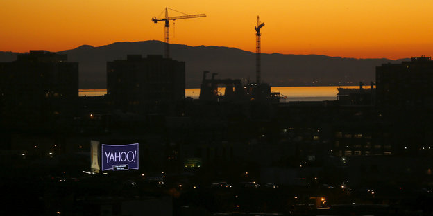 Panoramablick auf San Francisco bei Sonnenaufgang, ein Yahoo-Schild leuchtet in der dunklen Häusermasse