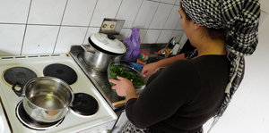 Eine Frau steht an einem Kochtopf