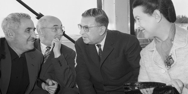 Ein schwarz-weiß Bild zeigt vier ältere Menschen, drei Männer und eine Frau, die sich lachend unterhalten