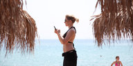 Eine Touristin unter griechischen Palmen bedient ihr Handy
