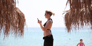 Eine Touristin unter griechischen Palmen bedient ihr Handy
