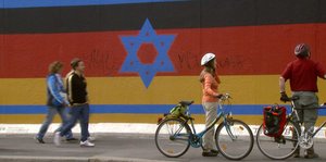 Eine Collage am Rest der Berliner Mauer: Die deutsche und die israelische Flagge liegen übereinander