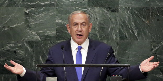 Benjamin Netanjahu mit ausgebreiteten Armen an einem Rednerpult