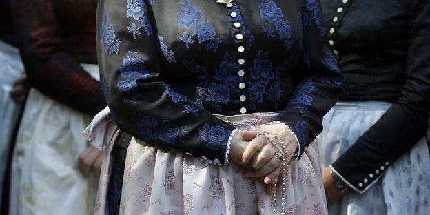 Eine Frau in bayerischer Tracht faltet die Hände vor dem Bauch