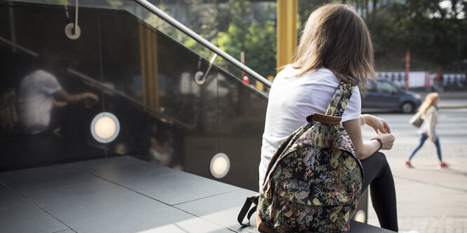 Eine Frau sitzt mit einer Tasche auf einer Treppe