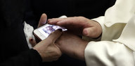 Hände legen sich schützend über ein Smartphone