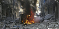 ein brennendes Fahrzeug in einer völlig zerstörten Straße in Aleppo