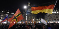 Menschenmenge mit Flaggen im Dunkeln bei Pegida in Dresden