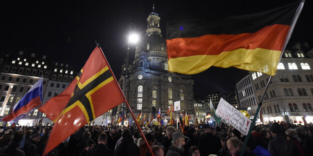 Menschenmenge mit Flaggen im Dunkeln bei Pegida in Dresden