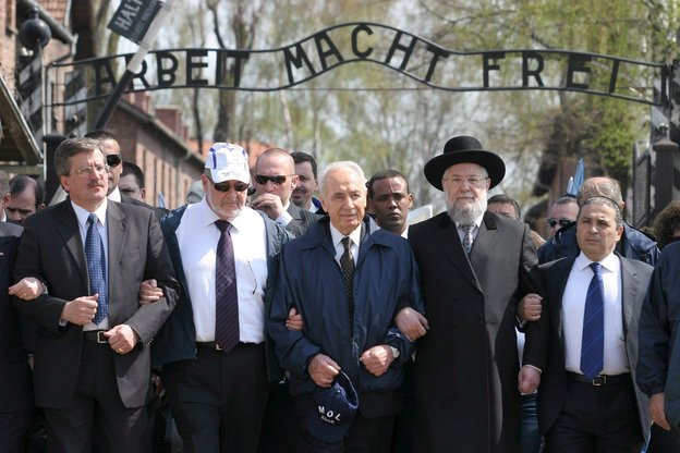 Schimpn Peres eingehakt mit anderen Teilnehmern vor der Aufschrift "Arbeit macht Frei" auf dem Boden des ehemaligen Konzentrations- und Vernichtungslagers Auschwitz-Birkenau