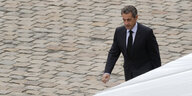 Ein Mann läuft über Pflasterstein. Es ist Nicolas Sarkozy