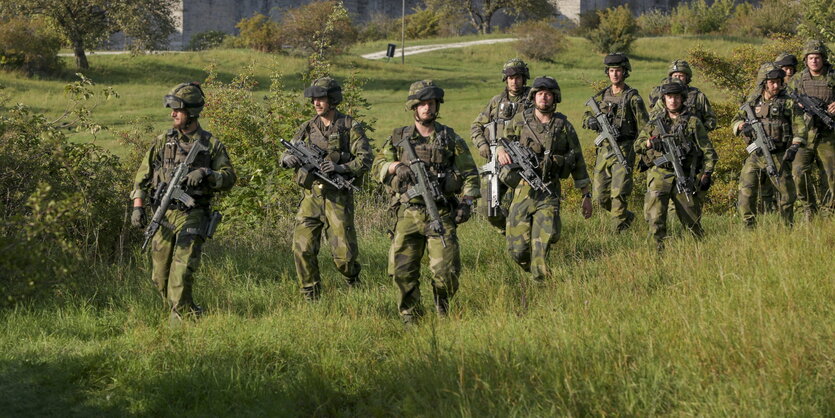 Ein schwedische Truppe Soldaten läuft durch Gras