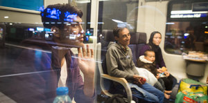 Drei Flüchtlinge sitzen in einem Sonderzug