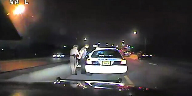 Eine Autokamera filmt zwei Polizisten an einem Auto