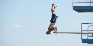 ein Mann macht Handstand auf einem Sprungturm