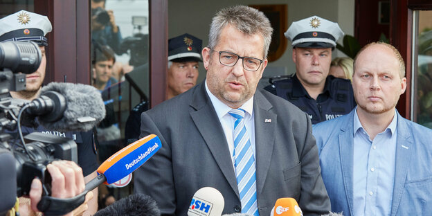 Der Innenminister von Schleswig-Holstein, Stefan Studt, spricht vor einer Tür in Fernsehkameras